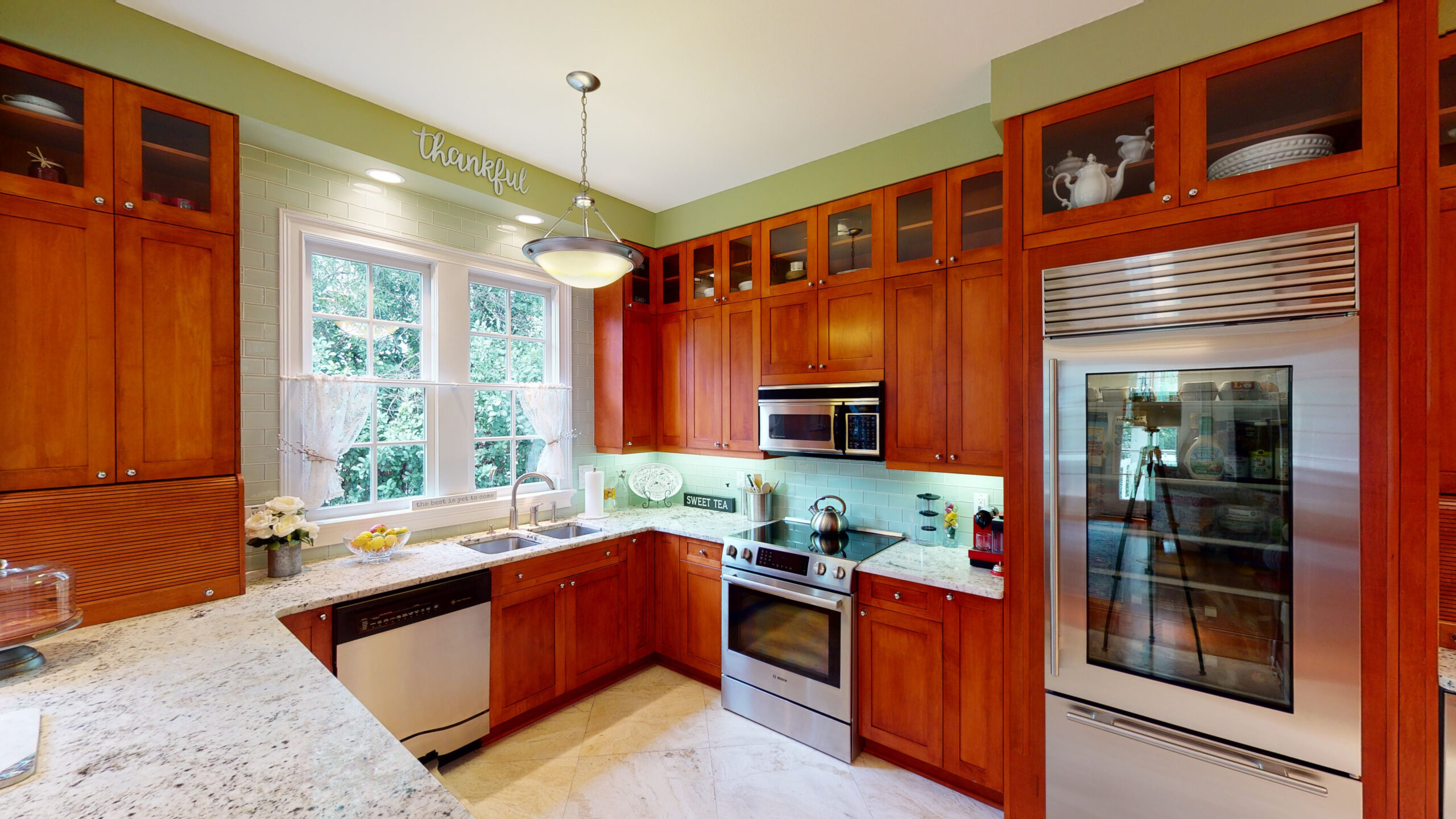 A kitchen with wooden cabinets and marble counters