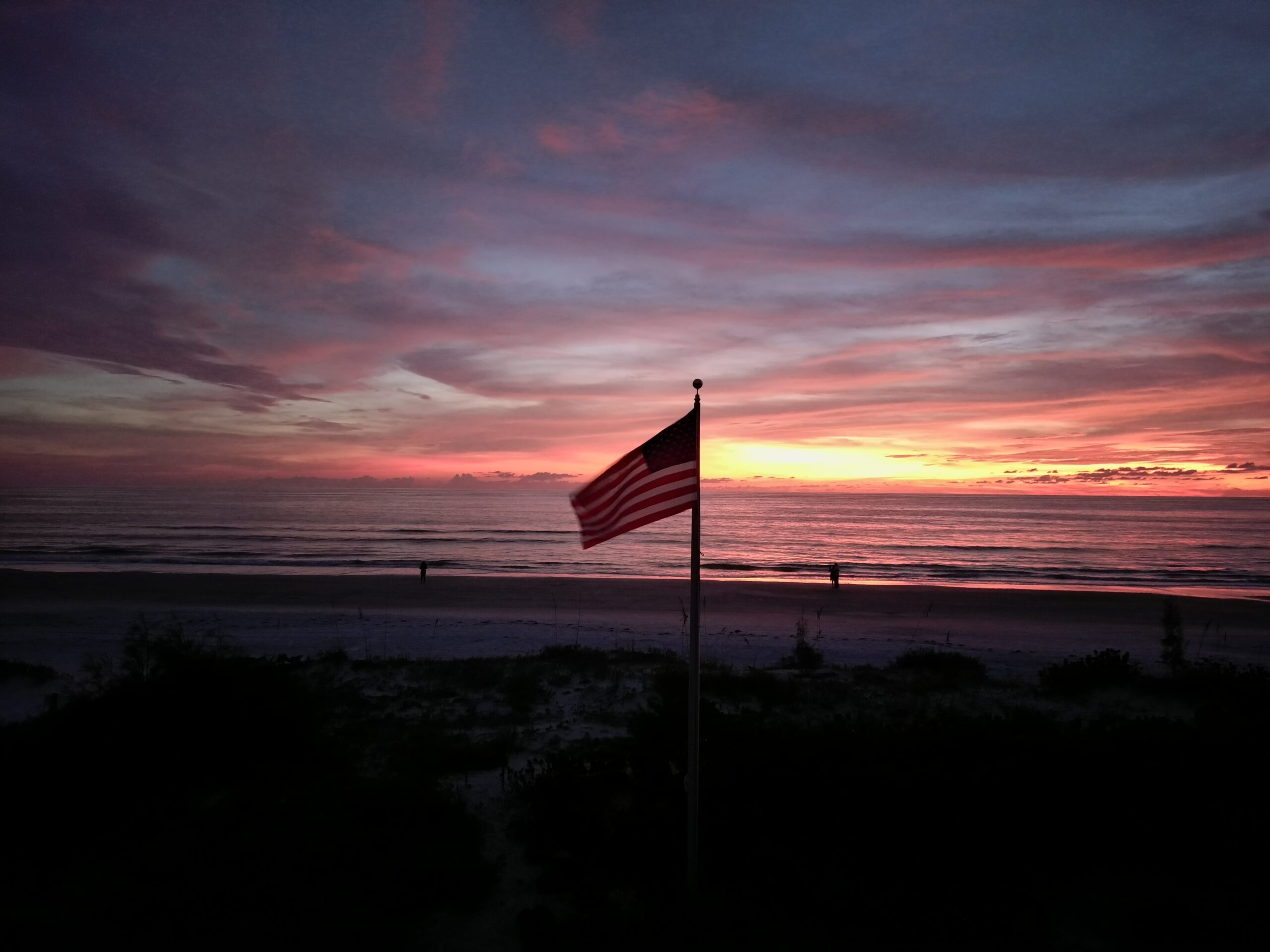 An American flag planted on a beach shore
